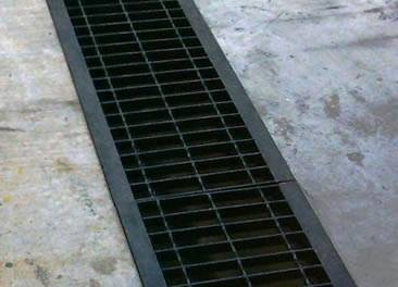 A painted carbon steel grating is covering a trench.