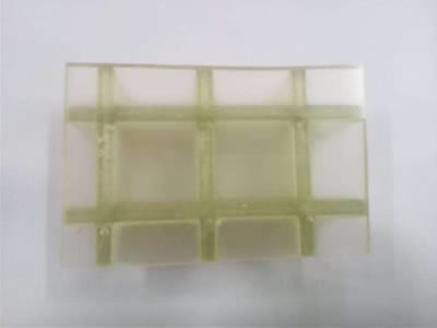 A piece of transparent covered FRP grating on the gray background.