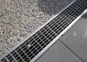 A stainless steel grating is covering a trench.