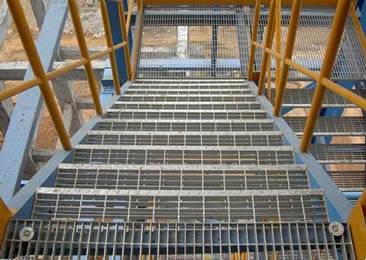 Several steel grating stair treads are installed in the construction site.