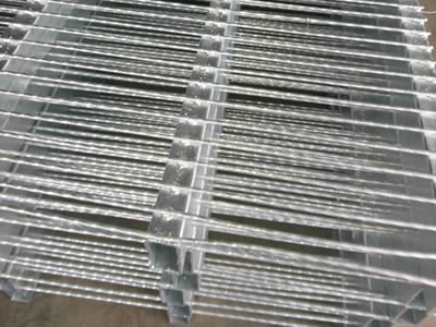 Several pieces of hot dipped steel bar grating on the ground.