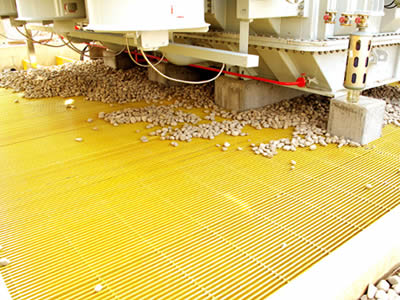 Yellow color transformer gratings are lay on the transformer bay and several stones on them.