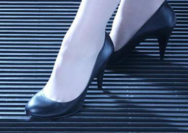 A woman wearing high-heeled shoes is standing on the close mesh walkway grating.