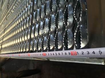 A hand is measuring the grating length of the diamond safety grating by meter ruler.