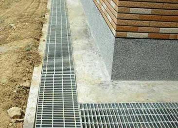 Several aluminum steel gratings are covering the trench surrounding the house.