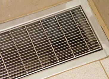 A stainless steel close mesh grating is covering a trench.