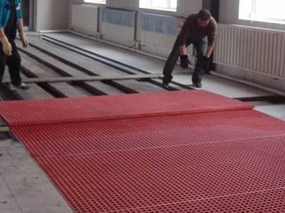 Two workers are installing red FRP grating.