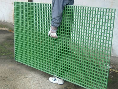 A worker is holding a piece of green color FRP molded grating.