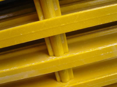 A piece of yellow color shaped bar FRP pultruded grating on the gray background.