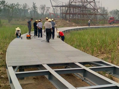 Several workers stepping on the steel grating walkway.