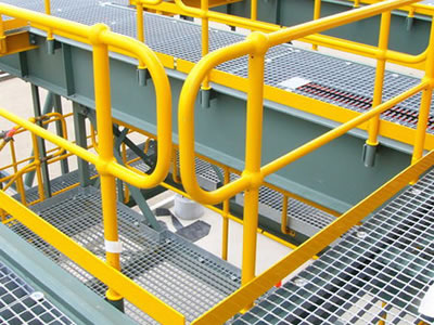 Steel grating with yellow handrail with toe plate under of it.
