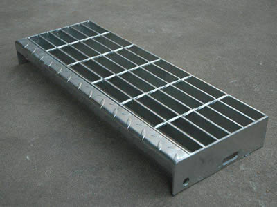 A bolted fixing steel grating with checker plate nosing on the ground.
