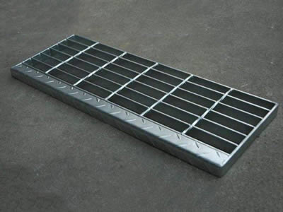 A weld fixing steel grating with checker plate nosing on the ground.